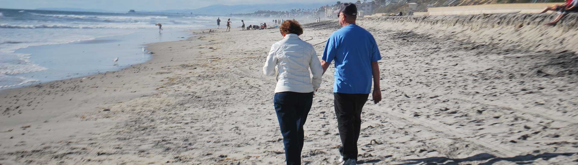 Senior couple holding hands walking on a beach